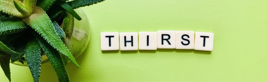 THIRST spelled out in tiles beside small plant